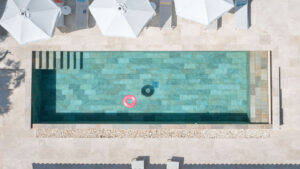 Luchtfoto van het zwembad van een luxe villa aan de Côte d’Azur met witte parasols en ligbedden – zomerse elegantie en rust.