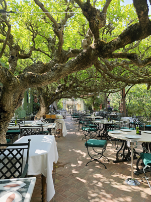 Buitenterras van Restaurant Bruno met overhangende takken die schaduw geven, sfeervol gedekte tafels en een warme Provençaalse ambiance