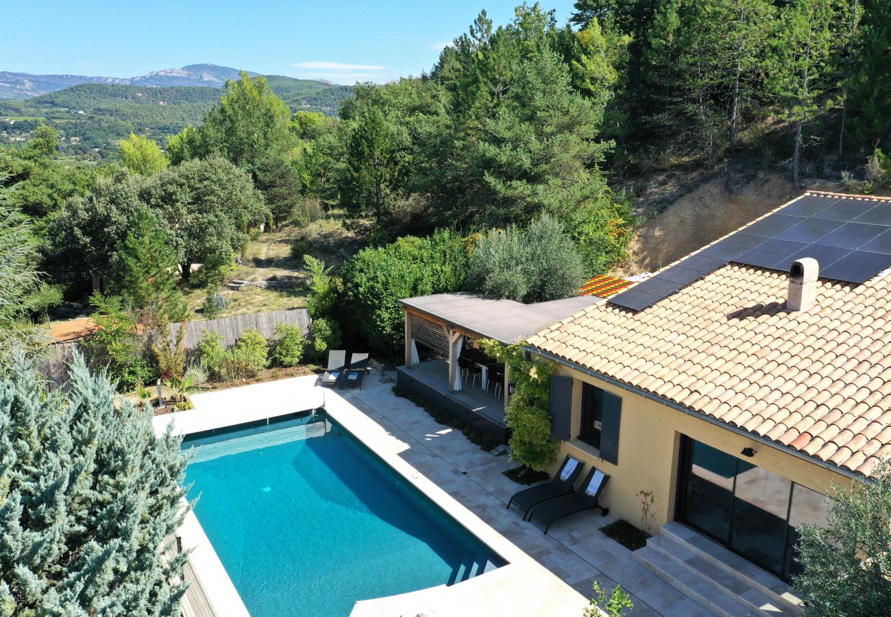 Luftaufnahme, die unsere Ferienvilla, überdachte Terrasse, Pool und malerische Berglandschaft zeigt.