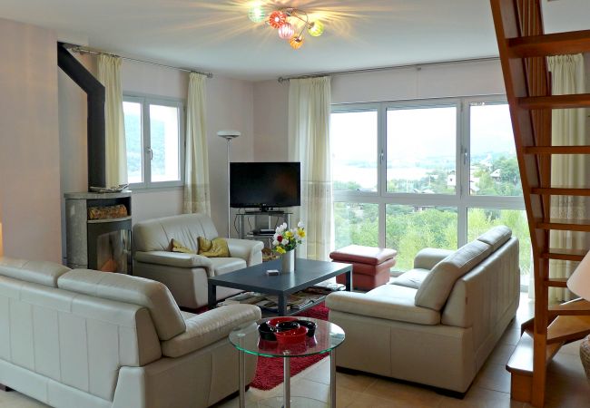 Wohnzimmer mit Holzofen, Flachbildfernseher und Blick auf See und Berge bei Villa Dalaromeri