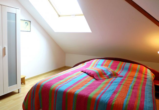 Entdecken Sie ein ordentliches Schlafzimmer mit einem Doppelbett und viel Licht vom Dachfenster