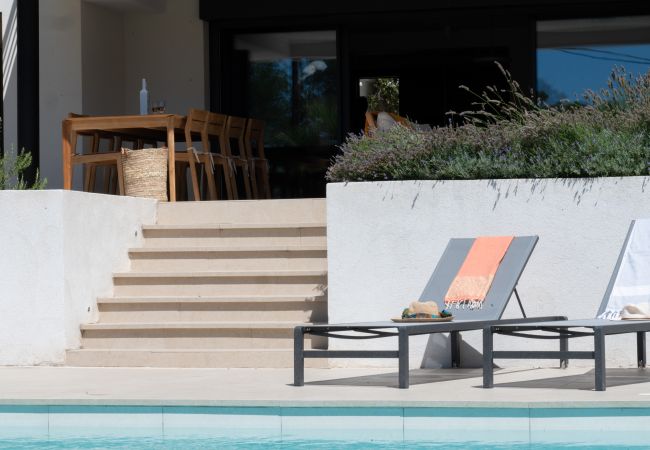 Villa Le 41 - Herausgezoomtes Foto vom Pool, Liegestühlen, Treppe zur überdachten Terrasse mit Esstisch und Wein