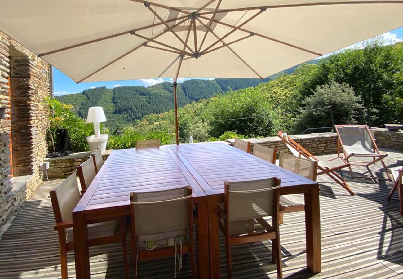 Terrassenessen bei La Bastide 48BAST, mit einem großen Esstisch, Sonnenschirm und einer atemberaubenden Panoramaaussicht
