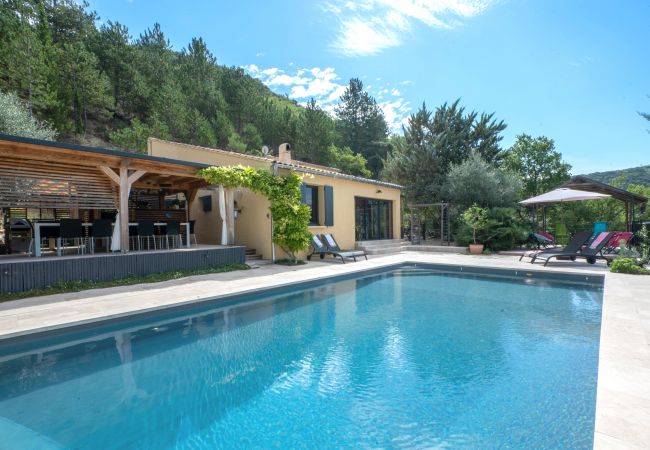 Exterior view of our holiday villa with covered terrace, dining table, bar, and heated private pool.