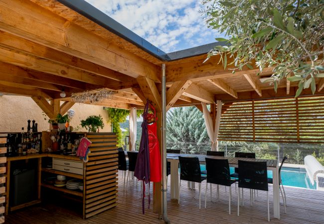Vue de la terrasse couverte avec bar, table à manger et vue sur la piscine dans notre villa de vacances.