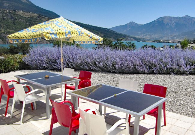 Terrasse avec table à manger, buissons de lavande, et vue sur le lac et les montagnes à la Villa Dalaromeri