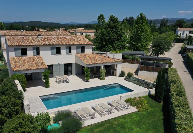 Vue aérenne de la Villa Beaumont avec piscine, terrasse ensoleillée, jardin et abri voiture, entourée de verdure luxuriante