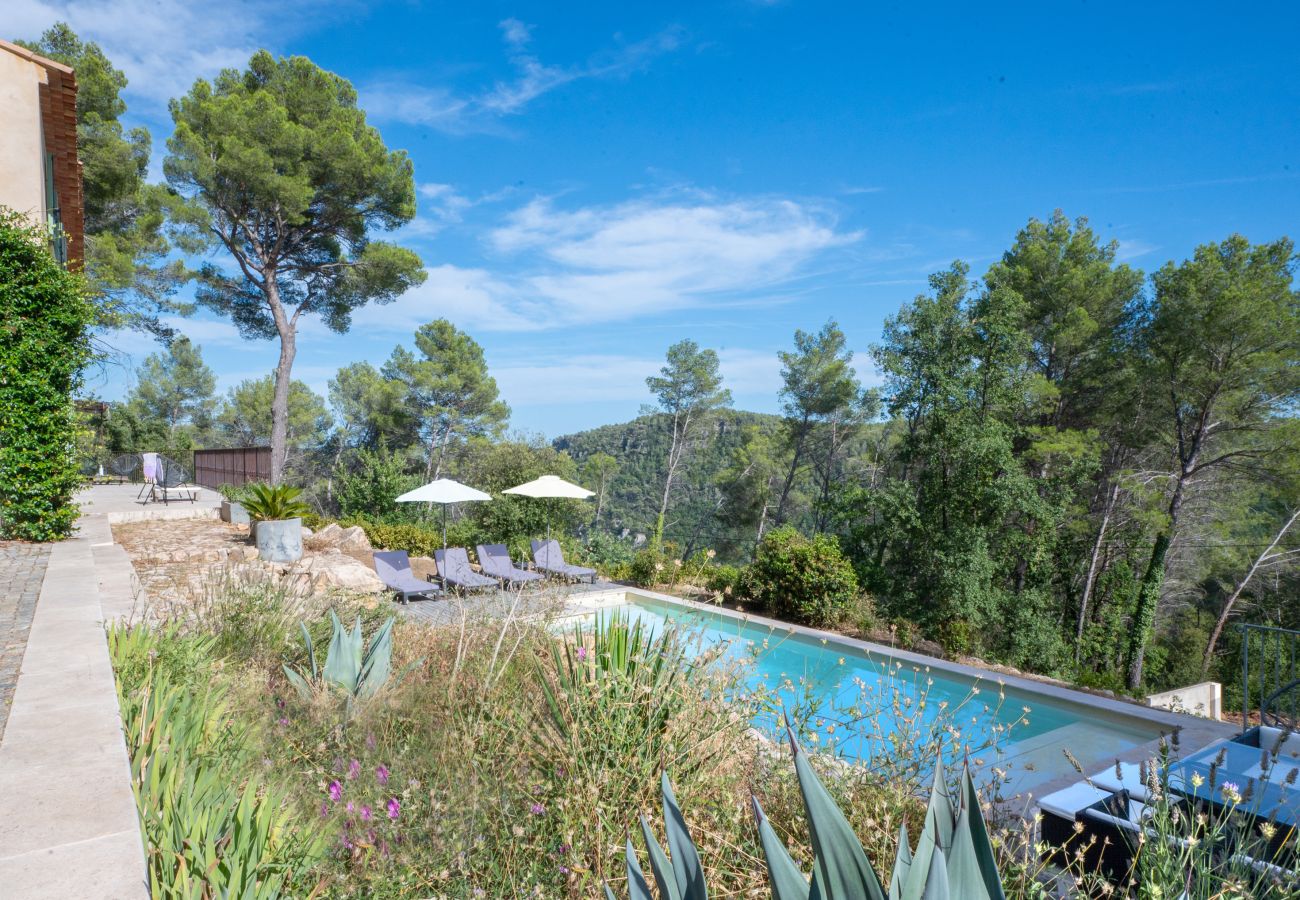 Détente au bord de la piscine de la Villa Tourrettes avec chaises longues, parasols, coin repas et vue panoramique.