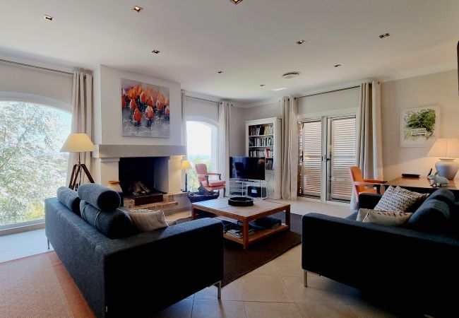 Foto van woonkamer met comfortabele zithoek bij de open haard, zeezicht via de ramen bij Villa 83MAUR