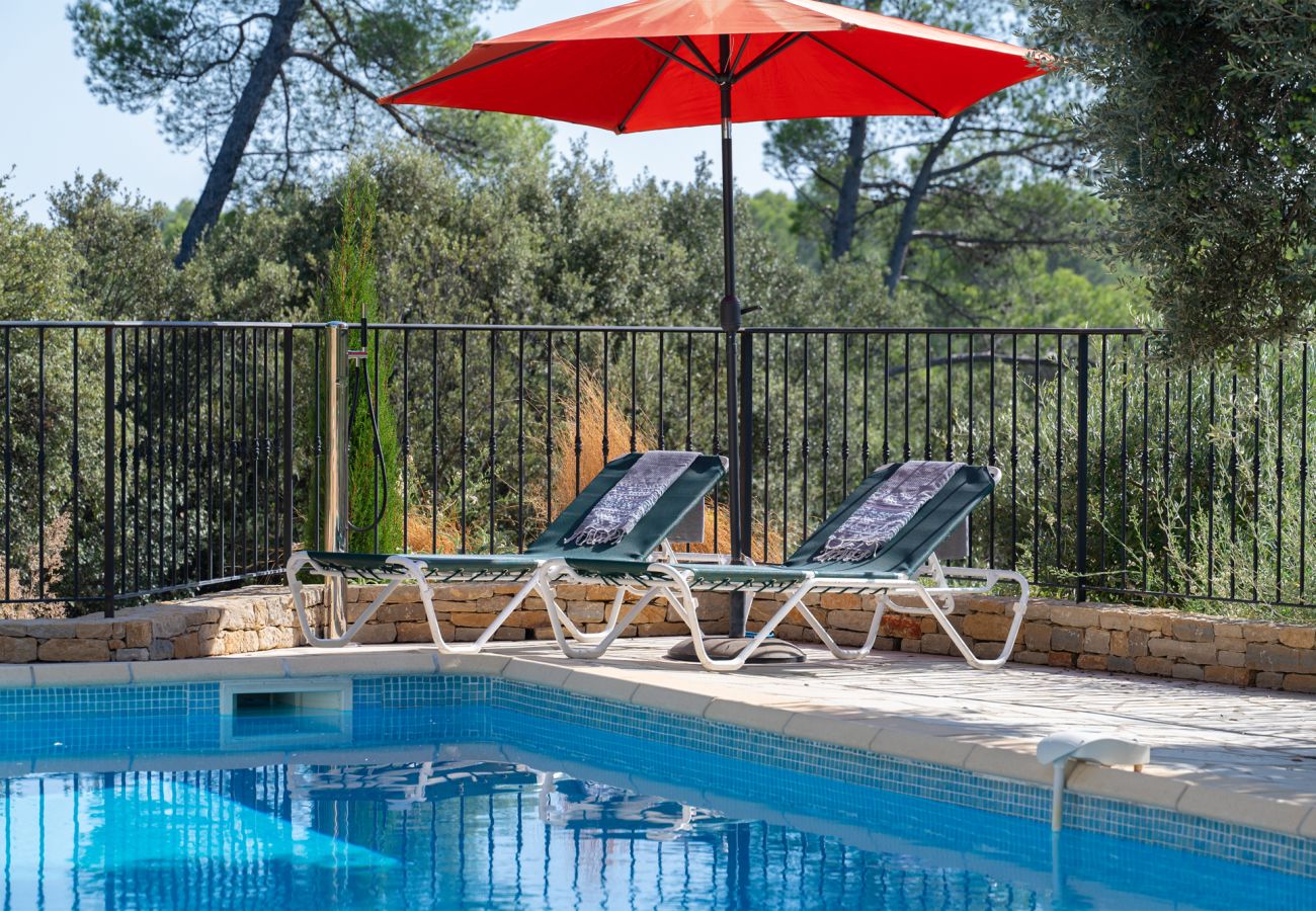 Close-up van het zwembad bij Villa Sygu met twee ligbedden, een parasol en een buitendouche in de rustige Provence