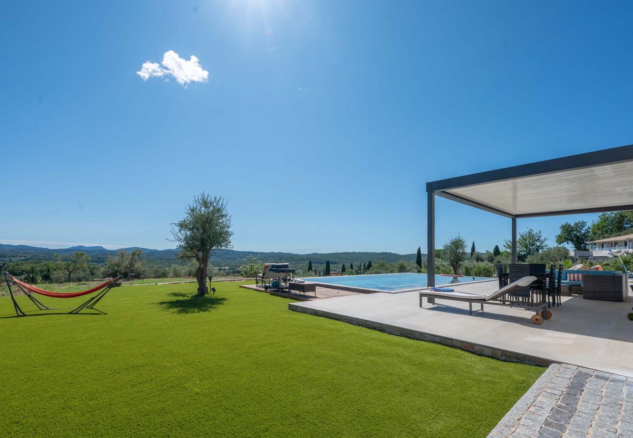 Gazon met hangmat, spiegelzwembad, overdekt terras en bergzicht bij Villa Belletoile in de Provence.